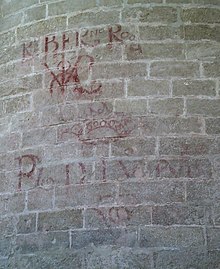 Faded red letters on a stone wall.