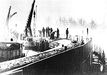 Black and white photo of construction workers, cranes and other equipement erecting the Berlin Wall