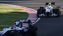 A white single-seater racing car is driven around a tarmac course.