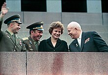 Photographie d'une tribune ou trois hommes en uniforme militaire avec les cosmonautes Youri Gagarine, Pavel Popovitch et Valentina Terechkova en 1963.