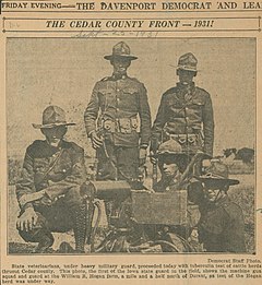 Five Iowa National Guardsmen in uniform posing by a machine gun