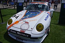 Vue avant de la 993 RSR n°84 du Perspective Racing. De couleur blanche, elle est sponsorisée par la marque de montres Hermès. Elle porte l'autocollant de course des 24 heures du Mans 1999 sur l'aile avant droite.