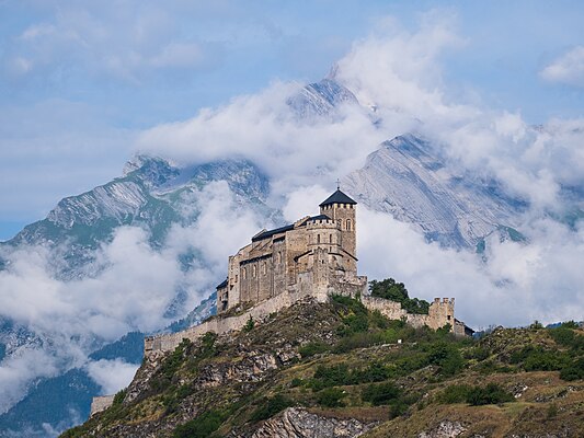 Igreja fortificada de Valère contra o fundo da montanha Haut de Cry, cantão de Valais, Suíça. Ela fica de frente para o castelo de Tourbillon, na colina oposta. O prédio principal é a Basílica de Notre-Dame de Valère. Construída nos séculos XI e XIII, era a residência dos cônegos do capítulo da catedral. Eles viveram aqui até a Revolução Francesa. As antigas dependências dos cônegos agora abrigam o Museu de História de Valais, fundado nesse local em 1883 e completamente reformado desde 2008. Valère recebeu o título de basílica menor durante a visita do Papa João Paulo II em 1984. (definição 5 456 × 4 092)