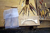 a small carved arch of wood with templates and carving tools around it