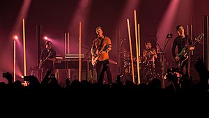 Queens of the Stone Age in 2017. Left to right: Dean Fertita, Josh Homme, Jon Theodore, and Michael Shuman. Not pictured: Troy Van Leeuwen.