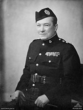 A middle aged man wearing military style dress and a Glengarry cap