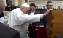 Pope Francis places his right hand on Benedict XVI's coffin and bows his head