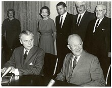 Diefenbaker and a Dwight Eisenhower sit at a table. Two women and three men stand behind them.