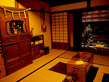 Museum room with wood furniture and cooking utensils in center