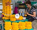 Étal et vendeuse de phuang malai dans un marché aux fleurs de Bangkok.