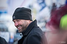 Portrait, de profil, très souriant, bonnet sur la tête.