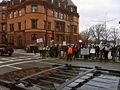 Protesters hold signs on the sidewalk next to the church