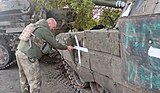 Soldier of the 17th Tank Brigade painting a cross on a captured tank