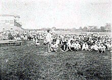 Dans un hippodrome, une foule de Coréens sont assis dans l'herbe.