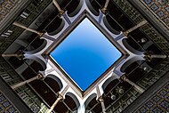 Sky seen from an open courtyard surrounded by tiled galleries