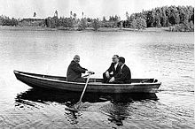 Photographie d'un petit canot sur un lac dans lequel se trouvent trois personnes. Khrouchtchev est en train de ramer.