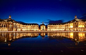 Photographie de la place de la Bourse illuminée qui se reflète dans le miroir d'eau.