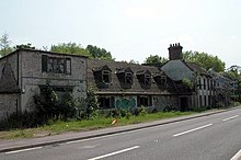 large two-storey derelict burnt-out building beside a road
