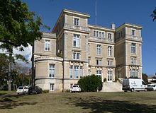 Photographie d'un bâtiment de quatre étages, crépis et bordures de pierre, de style classique à pilastres et colonnades. Ancienne villa "les Palmiers" rehaussée.