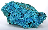 Crisocola azul-vivo em crescimento estalactítico e como uma camada fina dentro de uma rocha de tirolite (Mina de San Simon, Província de Iquique, Chile; tamanho: 14,1 x 8,0 x 7,8 cm).