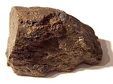 A brown block of irregular shape and surface, about 6 cm in size.