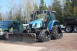 Tracteur 4x4, dont les roues sont remplacées par des chenilles.