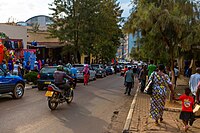 Photograph of a street scene including buildings, pedestrians and vehicles on the road