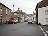 Street scene showing shops and houses with cars.