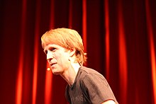 A blond man wearing a short black shirt