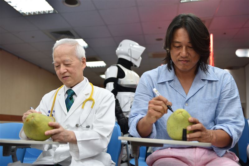 馬偕兒醫院長陳銘仁（左）與韓哥（右）手繪文旦，為馬偕兒醫中秋活動暖場。（圖／馬偕醫院提供）