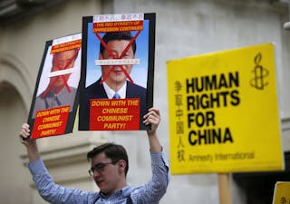 Human rights protesters hold up placards as they wait for China's President Xi Jinping to pass on the Mall during his ceremonial