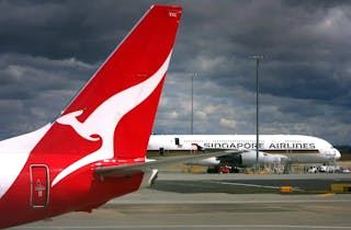 A Qantas Airways Boeing 737-800 plane passes a Singapore Airlines Airbus A380 at Sydney Airport