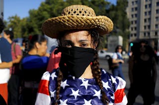 An activist depicting a farmer wears a U.S. flag during a rally against the Trans-Pacific Partnership (TPP) trade deal in front 