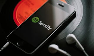 MALAGA, SPAIN - MARCH 5, 2018: Mobile phone with Spotify Music service in the screen and white earphones on a black vinyl record