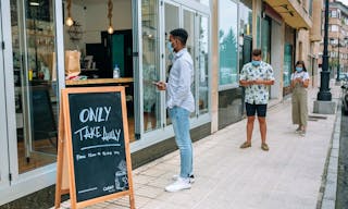 Row of people with masks maintaining social distance waiting to buy take away food