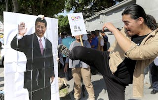 An activist kicks a portrait of Chinese President Xi Jinping during a protest against the upcoming meeting  between Taiwan's Pre