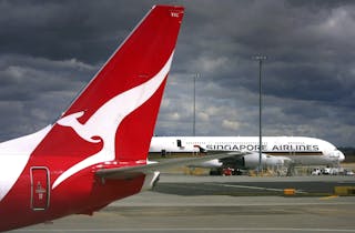 A Qantas Airways Boeing 737-800 plane passes a Singapore Airlines Airbus A380 at Sydney Airport