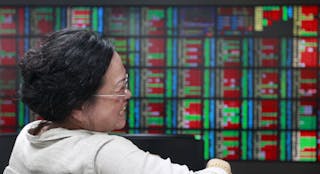 A woman laughs while monitoring stock market prices inside a brokerage in Taipei, Taiwan