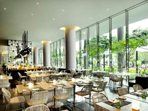 un restaurante con mesas, sillas y ventanas grandes en PARKROYAL COLLECTION Pickering, Singapore en Singapur