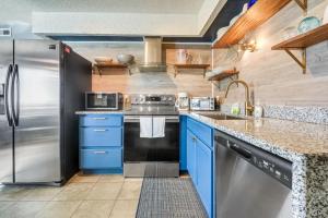 a kitchen with blue cabinets and a stainless steel refrigerator at The Beach Is Back in Myrtle Beach