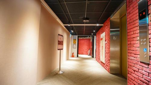 台北RF富裕自由商旅 - 忠孝馆的一条走廊,上面有红砖墙和一根杆