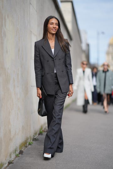 paris, france september 28 a guest wears a white top, a dark gray blazer jacket, flared suit pants, a black leather bag, white pointed shoes, outside givenchy, during the womenswear springsummer 2024 as part of paris fashion week on september 28, 2023 in paris, france photo by edward berthelotgetty images