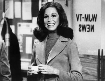 original caption still from the mary tyler moore show showing moore standing, smiling, inside of the wjm newsroom moore is shown from the waist up, holding a cup of coffee, circa 1975