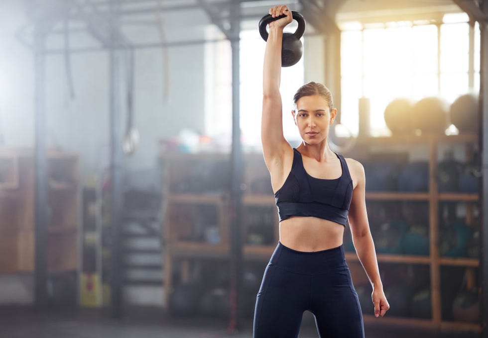 strong, powerful woman doing kettlebell weight lift exercise, workout or training in wellness gym sports person holding or exercising with fitness equipment for muscle, strength or health portrait