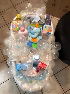 an arrangement of balloons and toys in a basket on the floor at a baby shower