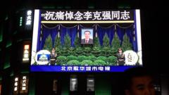 北京街头一大型电视屏幕在播出中国央视《新闻联播》有关李克强遗体告别式的片段（2/11/2023）