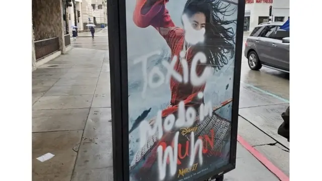 A Mulan film poster defaced with graffiti - a mask is painted over her face, along with the words "toxic made in Wuhan"