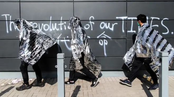 Unwell and injured protesters use emergency thermal blankets as they wait to take ambulances to leave the campus of the Hong Kong Polytechnic University in the Hung Hom district of Hong Kong on November 19, 2019. -