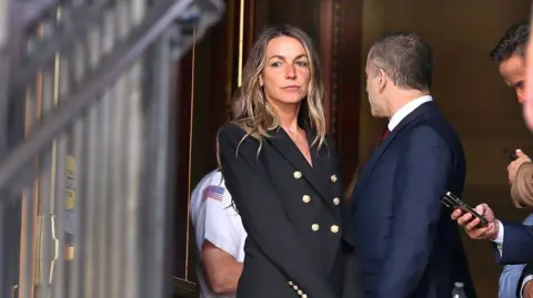 Karen Read stands in the doorway in a black pant suit