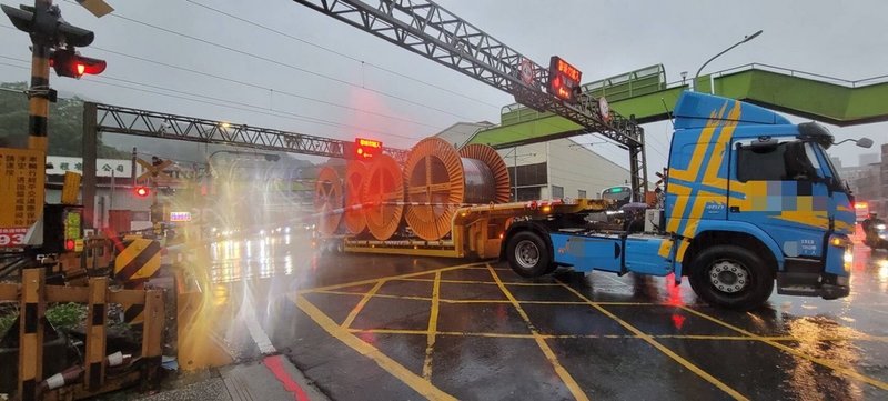 一輛載運大型電纜的拖板車6日行經新北市樹林區中山路與東佳路口平交道時，拖板車後輪卡在鐵軌間，前輪無法帶動前進，此時，平交道柵欄也剛好放下來，情況危急，幸經駕駛按下警示鈕，巡邏員警找來堆高機協助脫困，才避免可能發生的交通意外。（警方提供）中央社記者黃旭昇新北傳真  112年9月7日